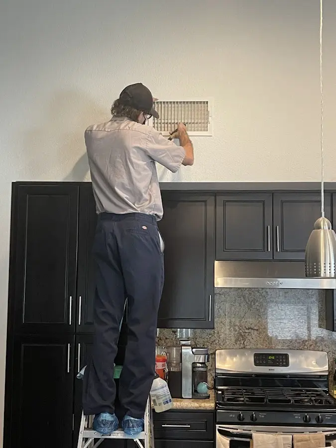 Technician inspecting an air vent during HVAC service in Coventry